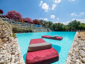 uma piscina com duas cadeiras vermelhas na água em Antica Masseria Rottacapozza em Torre San Giovanni Ugento