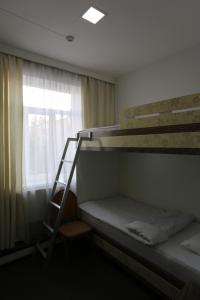 a bunk bed with a ladder next to a window at Sakura Inn in Fergana