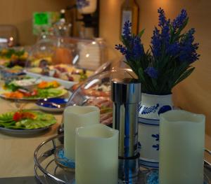 una mesa con platos de comida y un jarrón con flores púrpuras en Hotel Garni Sössaarep's Hüs, en Nebel