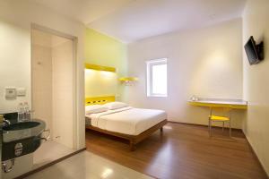 a bedroom with a bed and a bathroom with a sink at Ibis Budget Jakarta Menteng in Jakarta