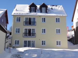 une maison blanche avec de la neige sur le toit dans l'établissement Appartements im Hollandhaus, à Kurort Oberwiesenthal