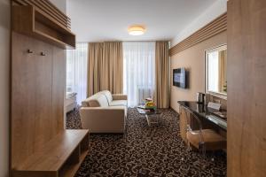 ein Hotelzimmer mit einem Sofa und einem Wohnzimmer in der Unterkunft Urpí­n City Residence in Banská Bystrica