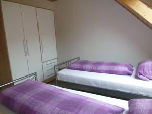 2 Betten in einem Zimmer mit lila Bettwäsche in der Unterkunft BodenSEE Apartment Meckenbeuren Hasenwinkel in Meckenbeuren