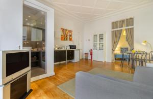 ein Wohnzimmer mit einem Sofa, einem TV und einem Tisch in der Unterkunft Chiado Balcony Apartment in Lissabon