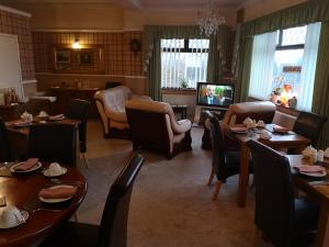 a dining room with tables and chairs and a television at East Mount House in Barrow in Furness