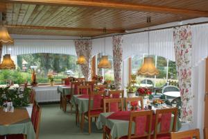 a dining room with tables and chairs and windows at Hotel und Cafe Panorama in Braunlage