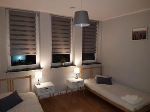 a bedroom with two beds and two windows at Arkadia Hostel in Mława