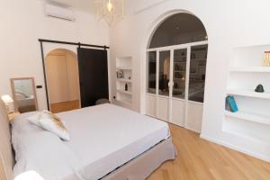 ein weißes Schlafzimmer mit einem großen Bett und einem Bogenfenster in der Unterkunft Luxury Laura Vatican Apartment ROMA CENTRO in Rom