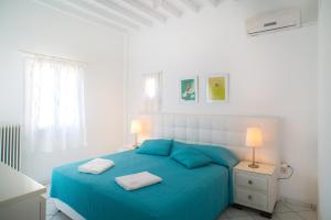 a white bedroom with a blue bed and two lamps at Adikri Villas & Suites in Tourlos