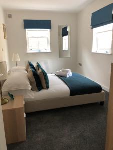 a bedroom with a large bed and two windows at Portfolio Apartments - St Albans City Centre in St. Albans