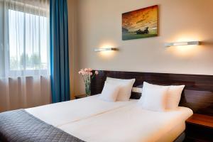 a bedroom with a bed with white sheets and a window at Focus Hotel Gdańsk in Gdańsk
