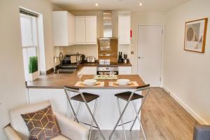 Portfolio Apartments - St Albans City Centre في سانت ألبانز: مطبخ مع طاولة و كرسيين في الغرفة