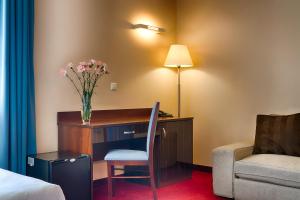 a hotel room with a desk with a vase of flowers on it at Focus Hotel Gdańsk in Gdańsk