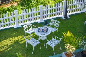 a table and chairs in a yard with a white fence at Hotel Mount Castle in Hatton