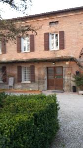 a large brick house with a brown door and windows at Agriturismo Dosso al Porto in Rolo
