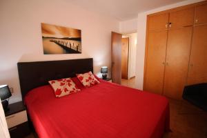 エンプリアブラバにあるBasic Comfort Apartment Gran Reserva 0078の赤いベッド1台(赤い毛布付)が備わるベッドルーム1室が備わります。