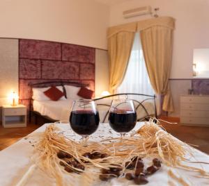 dos copas de vino tinto en una mesa en un dormitorio en Hotel Residence Confalone, en Nápoles