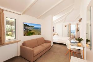 un soggiorno con divano, letto e scrivania di Hotel Villa Domizia a Porto Santo Stefano
