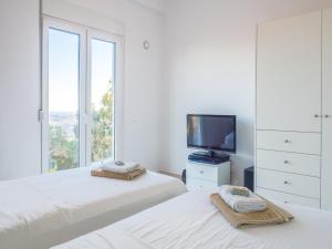 a white bedroom with two beds and a television at Villa Mariou in Plakias