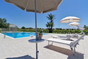 a patio with two chairs and an umbrella and a pool at Il Giardino dei Frangipani in Santa Croce Camerina