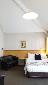 - une chambre avec un lit et un canapé en cuir noir dans l'établissement Cameron Thermal Motel, à Tauranga