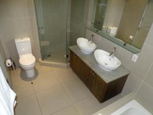 a bathroom with two sinks and a shower and a toilet at Chapman's Peak Penthouse in Hout Bay