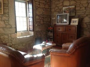 a living room with leather furniture and a tv at Casa Boavista in Paredes de Coura