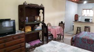 uma sala de estar com televisão e um quarto com mesa em Chalé em Ibitipoca em Conceição do Ibitipoca