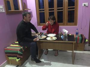 a man and a woman sitting at a table with food at CHÉRI HOME Stay in Khajurāho