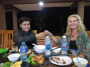 a man and a woman sitting at a table with food at Charm's Homestay in Phong Nha