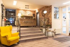 a lobby with stairs and a yellow chair at Altstadt-Hotel in Stendal