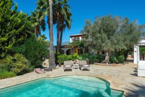 a swimming pool in a yard with palm trees and a house at New! Villa Can Colomaret Carmen in Santa Eularia des Riu