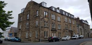 a large brick building with cars parked in front of it at Quiet, Convenient, Hawick Flat in Hawick