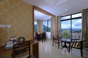 a dining room with a table and chairs and a large window at Tea Castle Munnar in Munnar