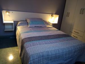 a bedroom with a bed with a striped blanket at Los Nietos Alojamientos in Mendoza