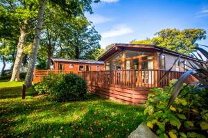 a cabin in the woods with a large deck at Coed Helen Holiday Park in Caernarfon