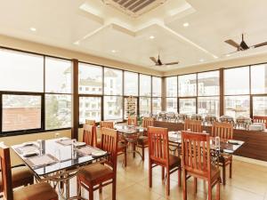 a restaurant with tables and chairs and large windows at Treebo Trend Goodland Residency in Trivandrum