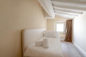 a white bed sitting in a room next to a window at Residenza D'Epoca La Basilica in Florence