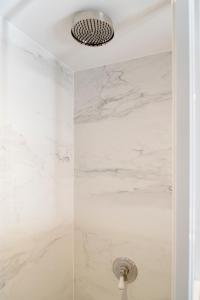 una doccia con pareti in marmo bianco e soffione di Getaway Studios "The Providence" Oostende a Ostenda