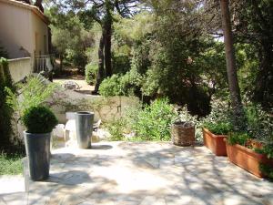 サントロペにあるPlage des Salins Parc des Salins St Tropezの鉢植えの植物と建物と木々が植えられたパティオ
