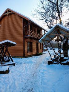 Una cabaña de troncos en la nieve con un columpio en Mandrivnyk, en Mykulychyn