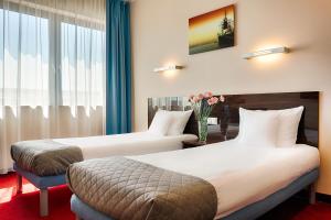 a hotel room with two beds and a vase of flowers at Focus Hotel Gdańsk in Gdańsk +31 photos