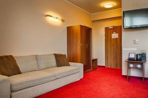 a living room with a couch and a flat screen tv at Focus Hotel Gdańsk in Gdańsk