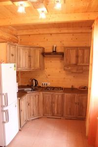 a kitchen with wooden cabinets and a white refrigerator at Медовий in Vorokhta +34 photos