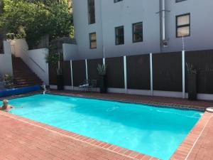 un homme nageant dans une piscine bleue dans l'établissement De Waterkant Piazza Apartments, au Cap