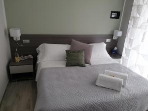 een slaapkamer met een groot bed met witte lakens en kussens bij Camomilla B&B in Alba