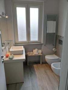 een badkamer met een wastafel, een toilet en een raam bij Camomilla B&B in Alba