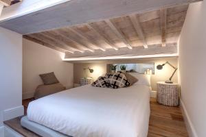 1 dormitorio con cama blanca y techo de madera en Mamo Florence - Parione Roof Terrace, en Florencia