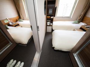 熊本市にあるNatural Hot Spring SUPER HOTEL Kumamoto Chamber of Commerceのベッド4台と窓が備わる客室です。