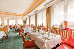 een restaurant met tafels, stoelen en ramen bij Hotel DreiSonnen in Serfaus